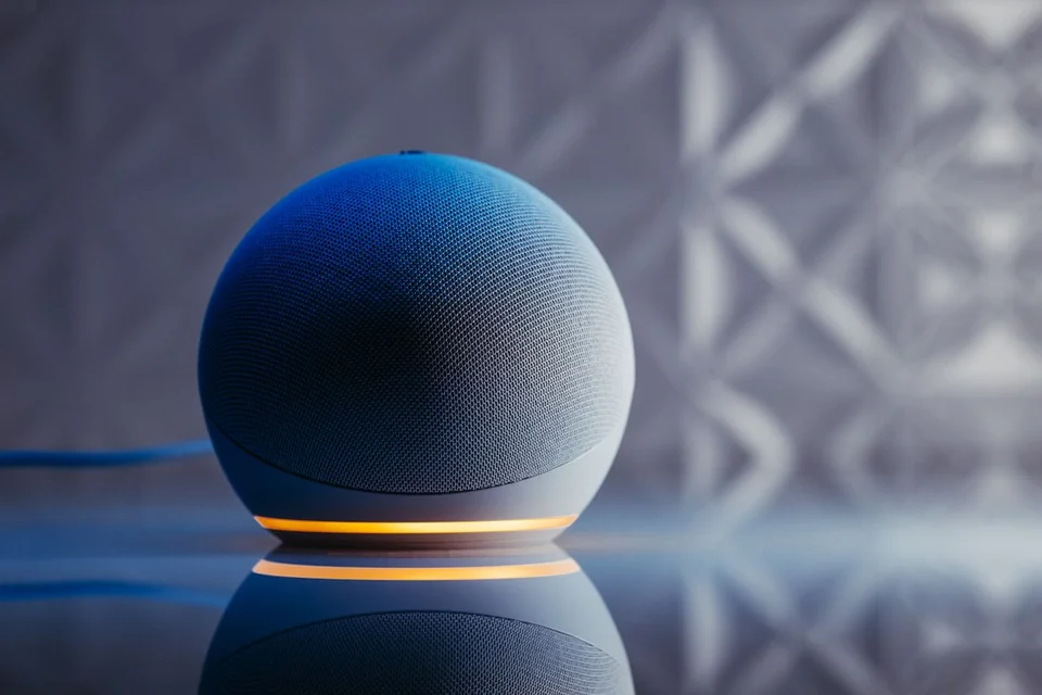 Een grijze bolvormige speaker met een stoffen bekleding en een verlichte ring